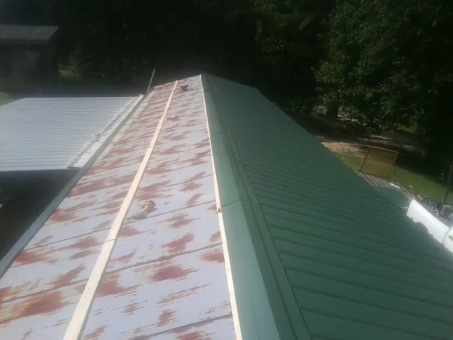 Old rusted panels beside newly installed green metal roofing in Naples